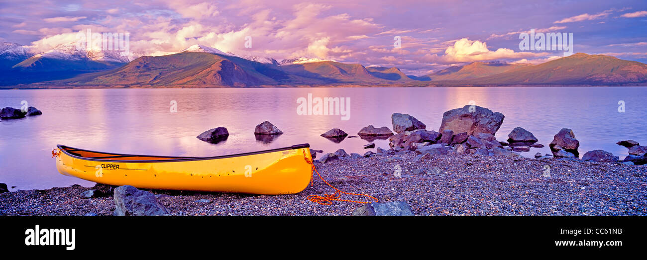 Yellow canoe on the shore of Kluane Lake at sunset with snow capped mountains in the background, Kluane National Park and reserv Stock Photo