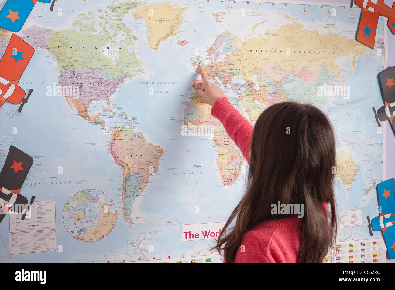 Young girl pointing to different countries on the world map Stock Photo