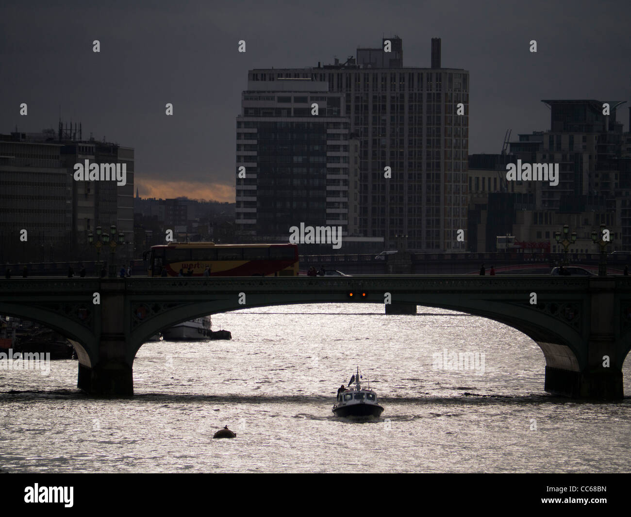 Boat passing under Lambeth Bridge over the Thames, London at dusk Stock Photo