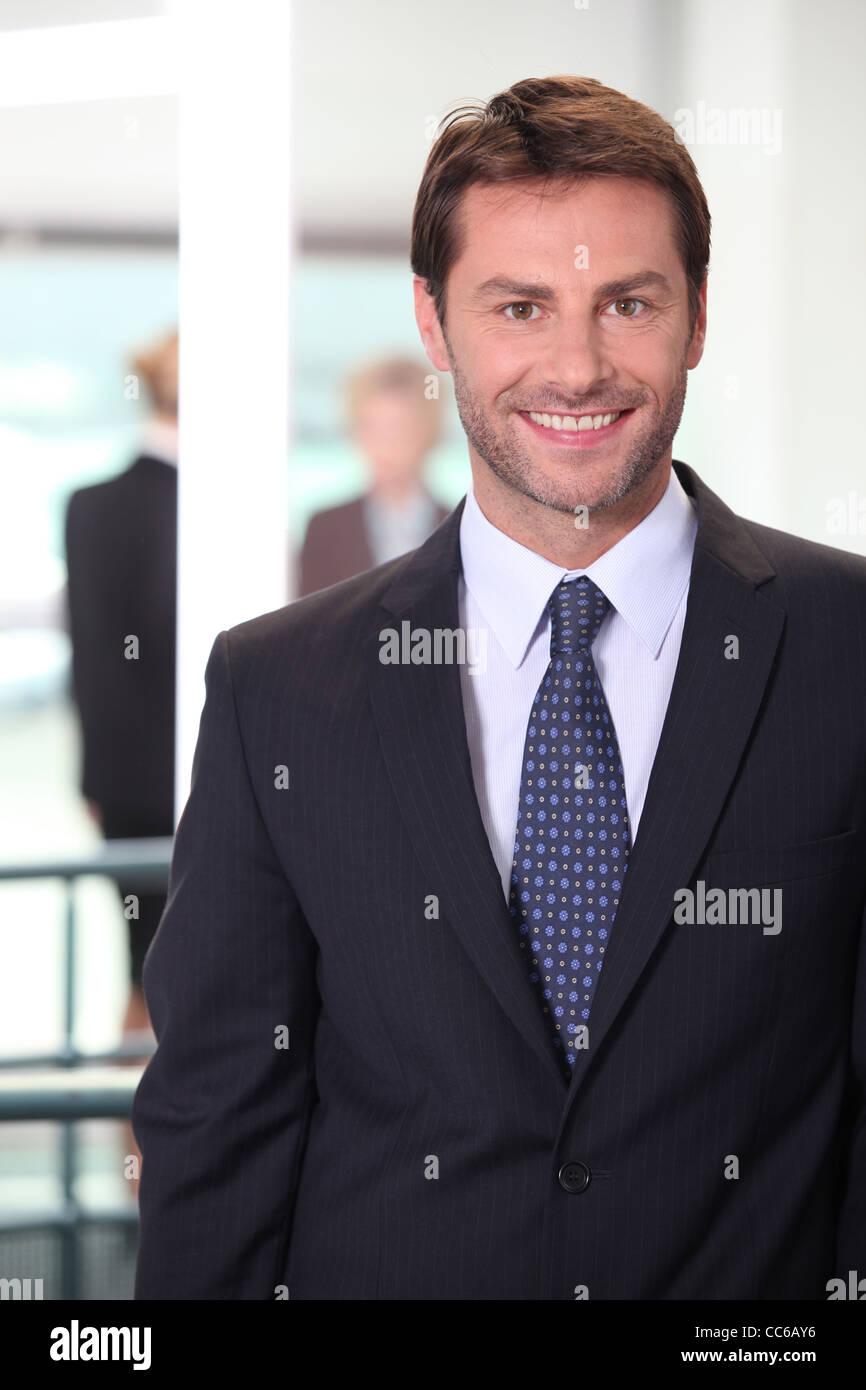 Smiling business man standing in an office building Stock Photo - Alamy