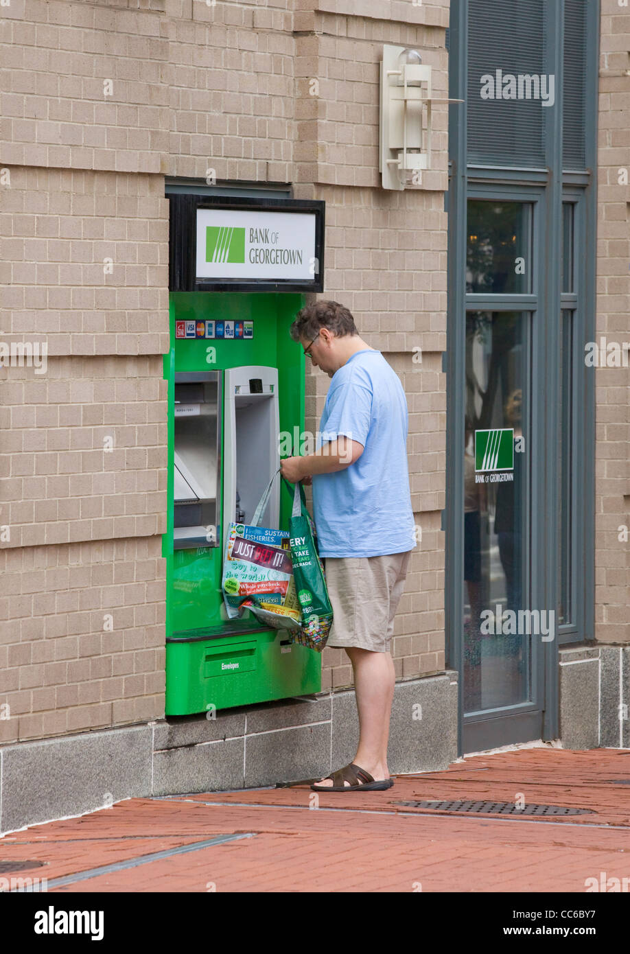 A Caucasian male using an ATM machine with shopping bag - USA Stock Photo