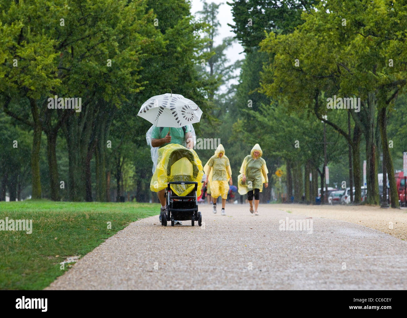 A man pushing a baby stroller in heavy rain Stock Photo