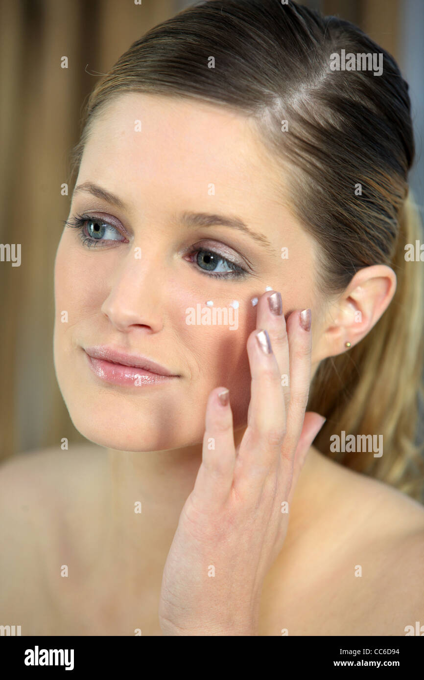 Pretty woman applying under-eye cream Stock Photo