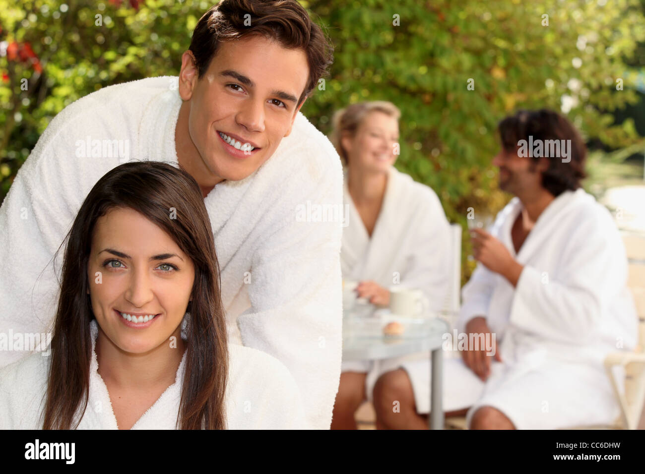 Two couple sat in garden wearing dressing gowns Stock Photo