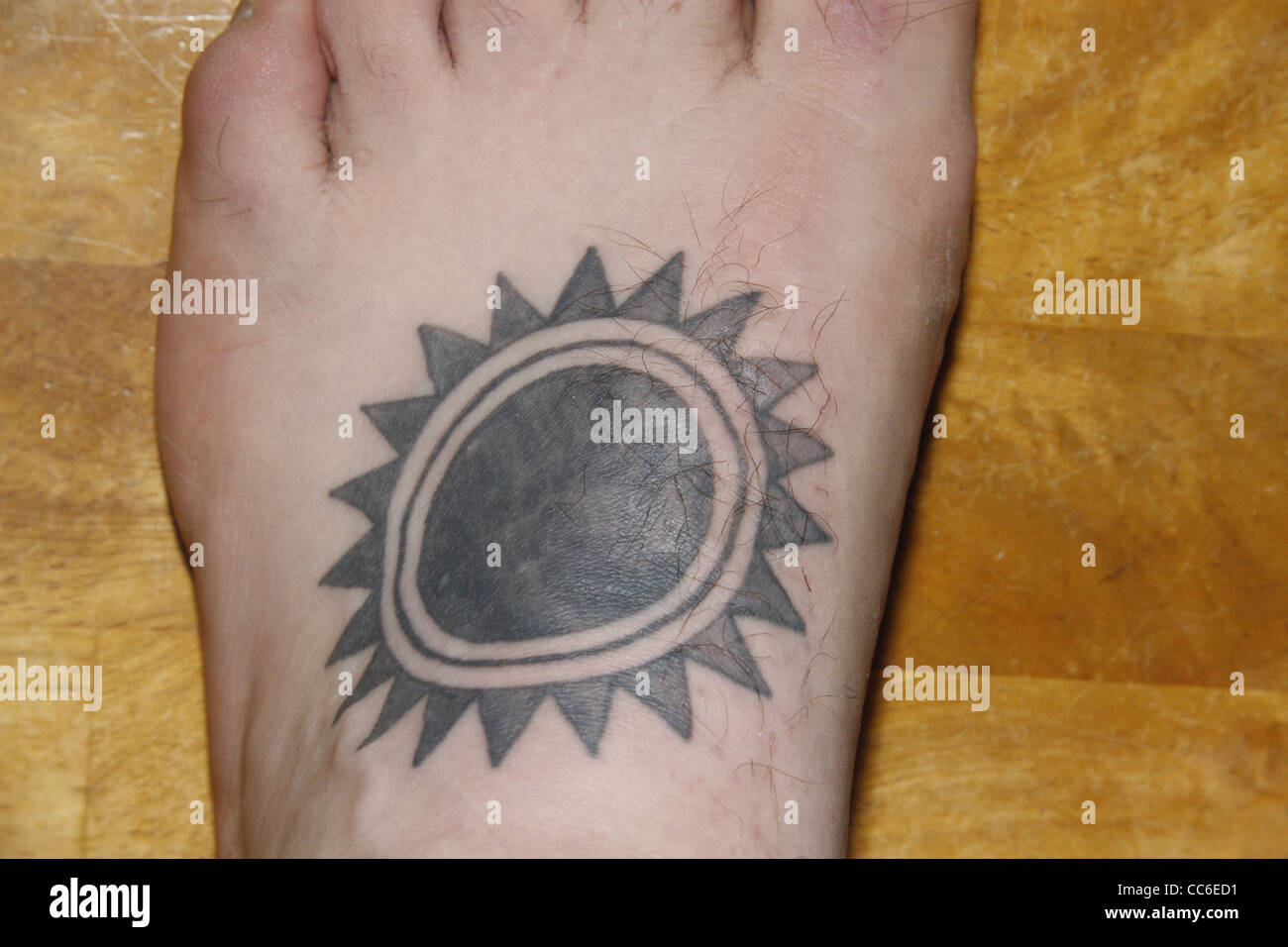 black sun tattoo on male foot Stock Photo