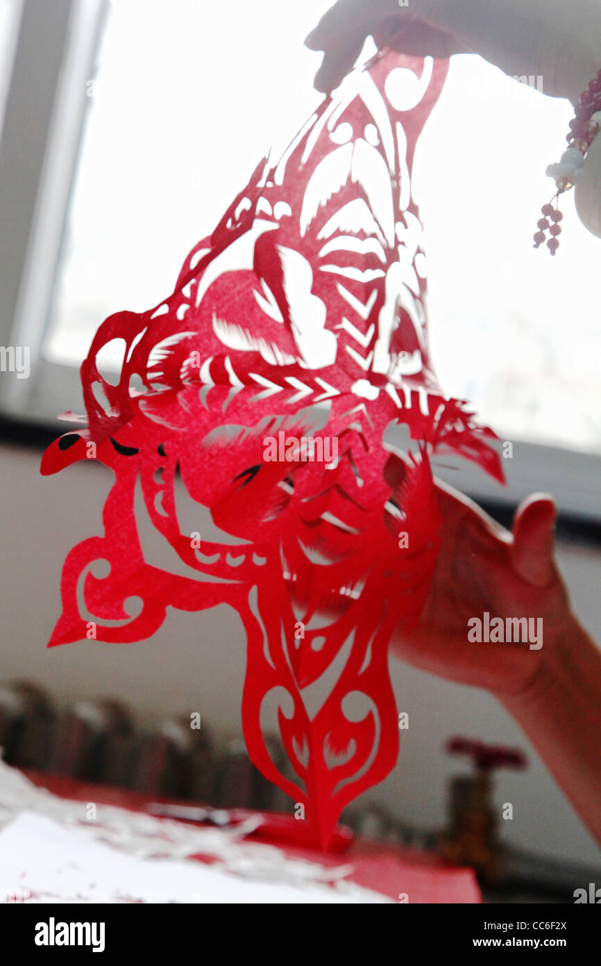 Woman unfolding a Chinese paper cutting, Beijing, China Stock Photo