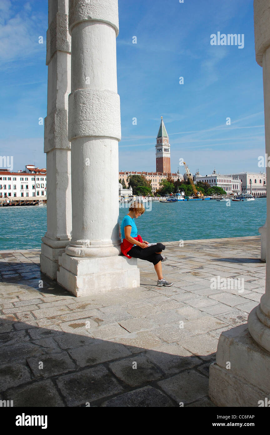 Caucasian woman reading book beside Lagoon, Venice, Italy Stock Photo