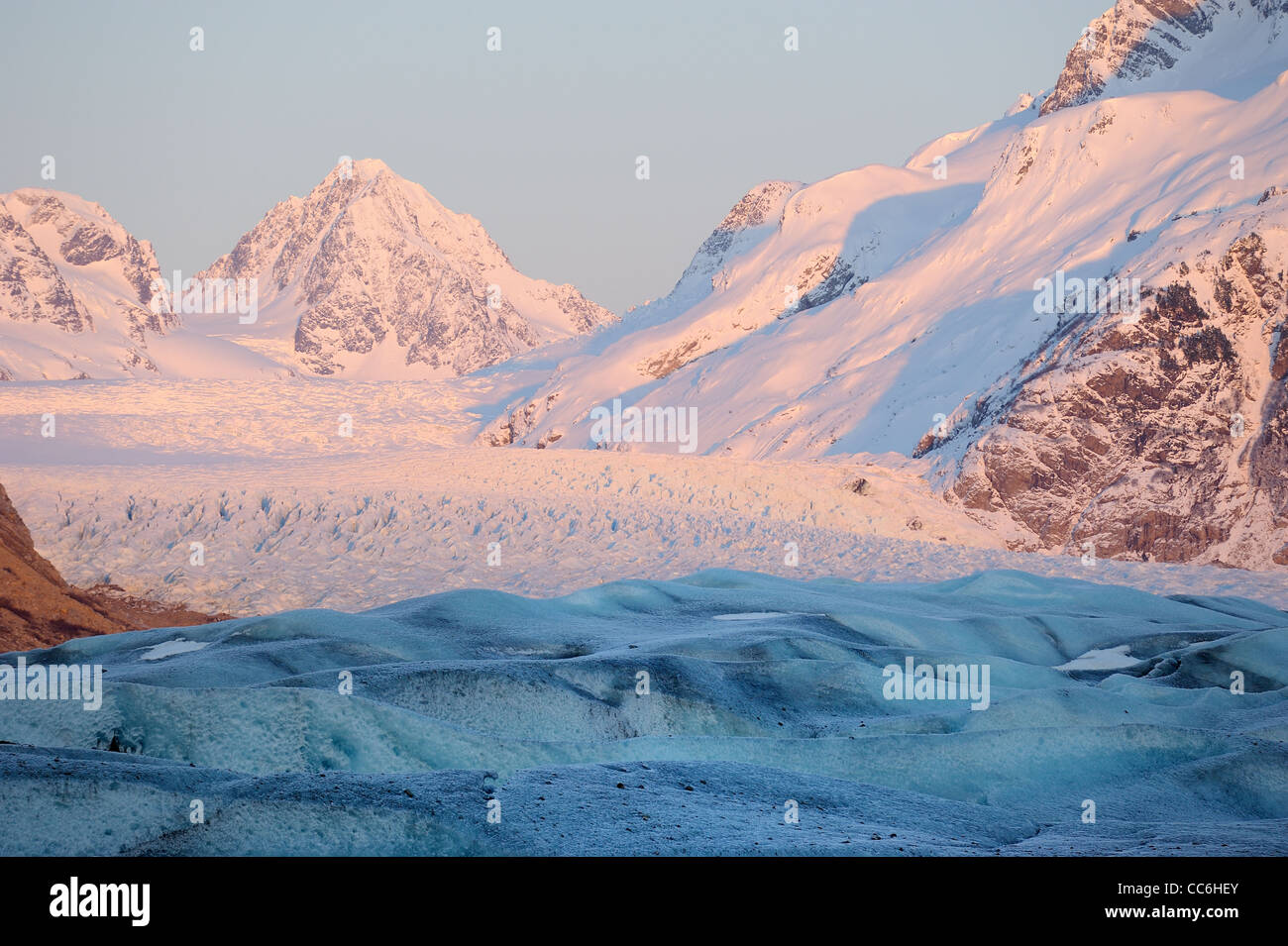 A glacier on mountains illuminated with soft pink evening light. Stock Photo