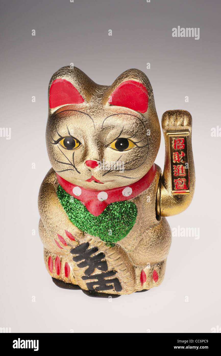 Maneki Neko, the beckoning cat - Japanese good fortune charm, with waving paw arm. Chinese made ornament. Stock Photo