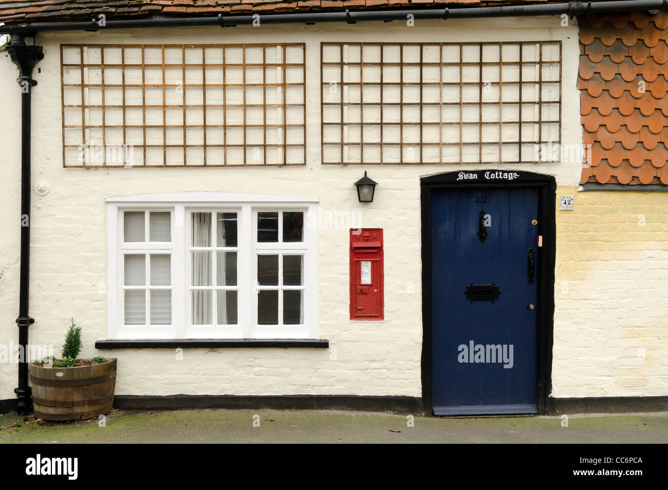 A terraced cottage in High Street Great Missenden with blue door and red post box set in wall. Stock Photo
