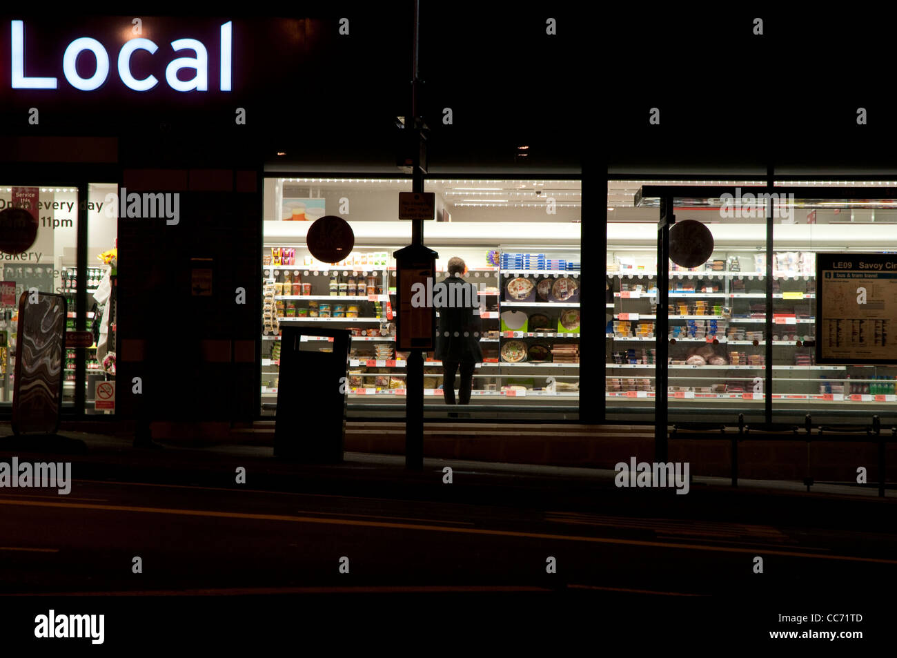 Man shopping in a small supermarket after dark, photographed from