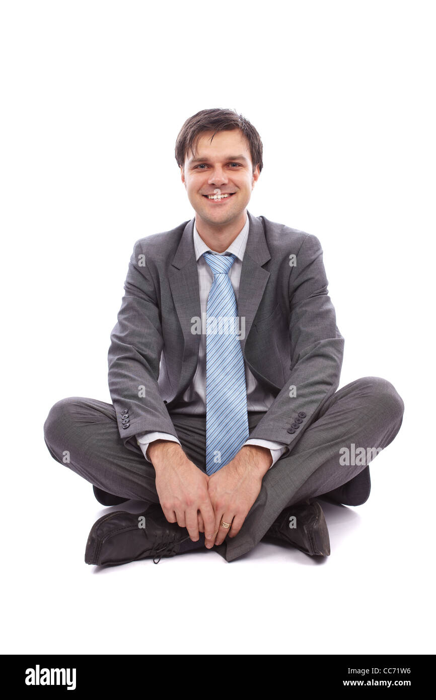 Young businessman sitting on the floor, isolated on white background ...