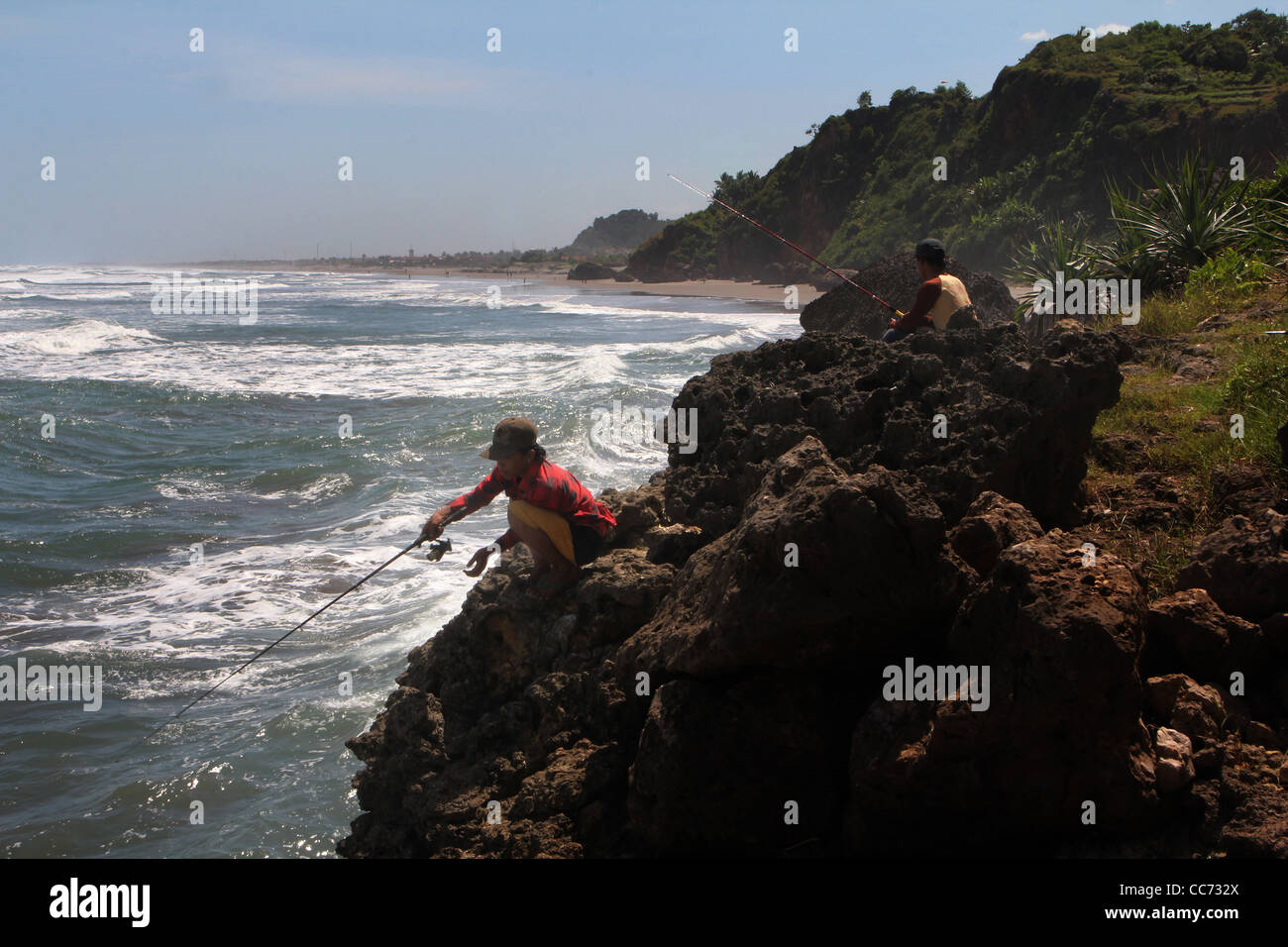 Teen boys fishing cliffs Parangtritis beach Java Indonesia indian ocean Yogyakarta Stock Photo