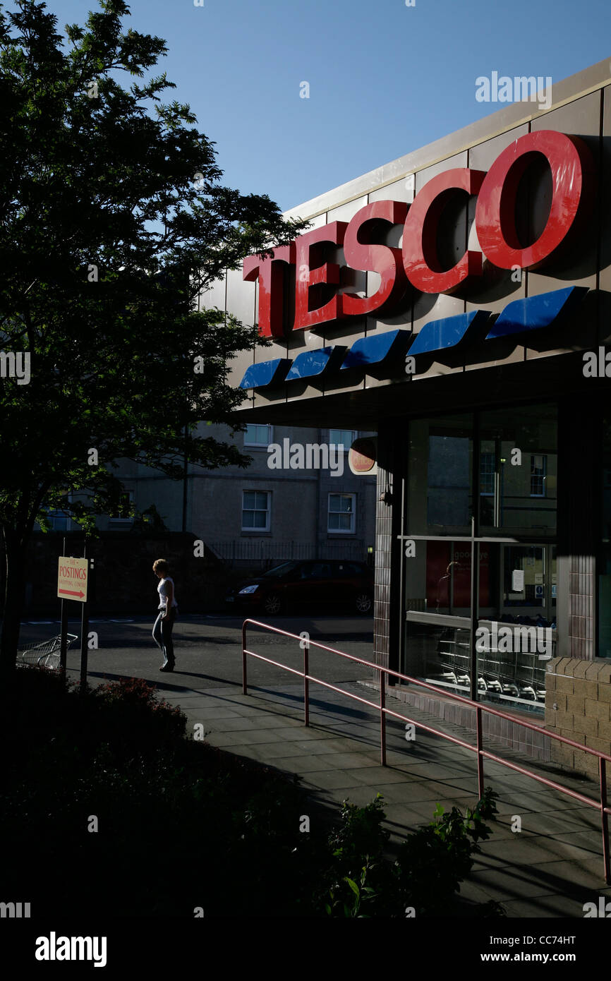 A  woman walks past the entrance to a Tesco store Stock Photo