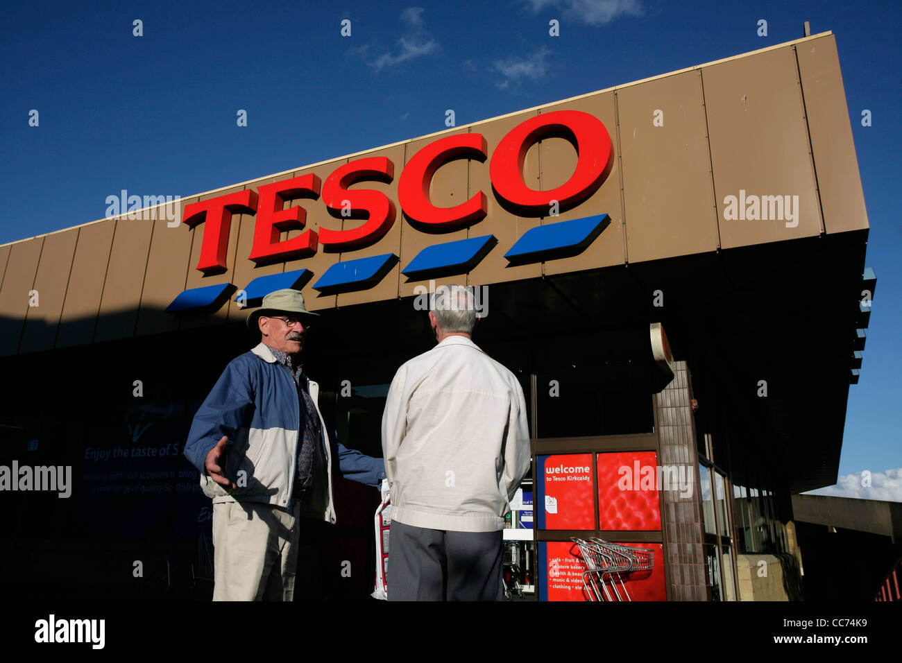 Two elderly men standing outside a Tesco supermarket Stock Photo