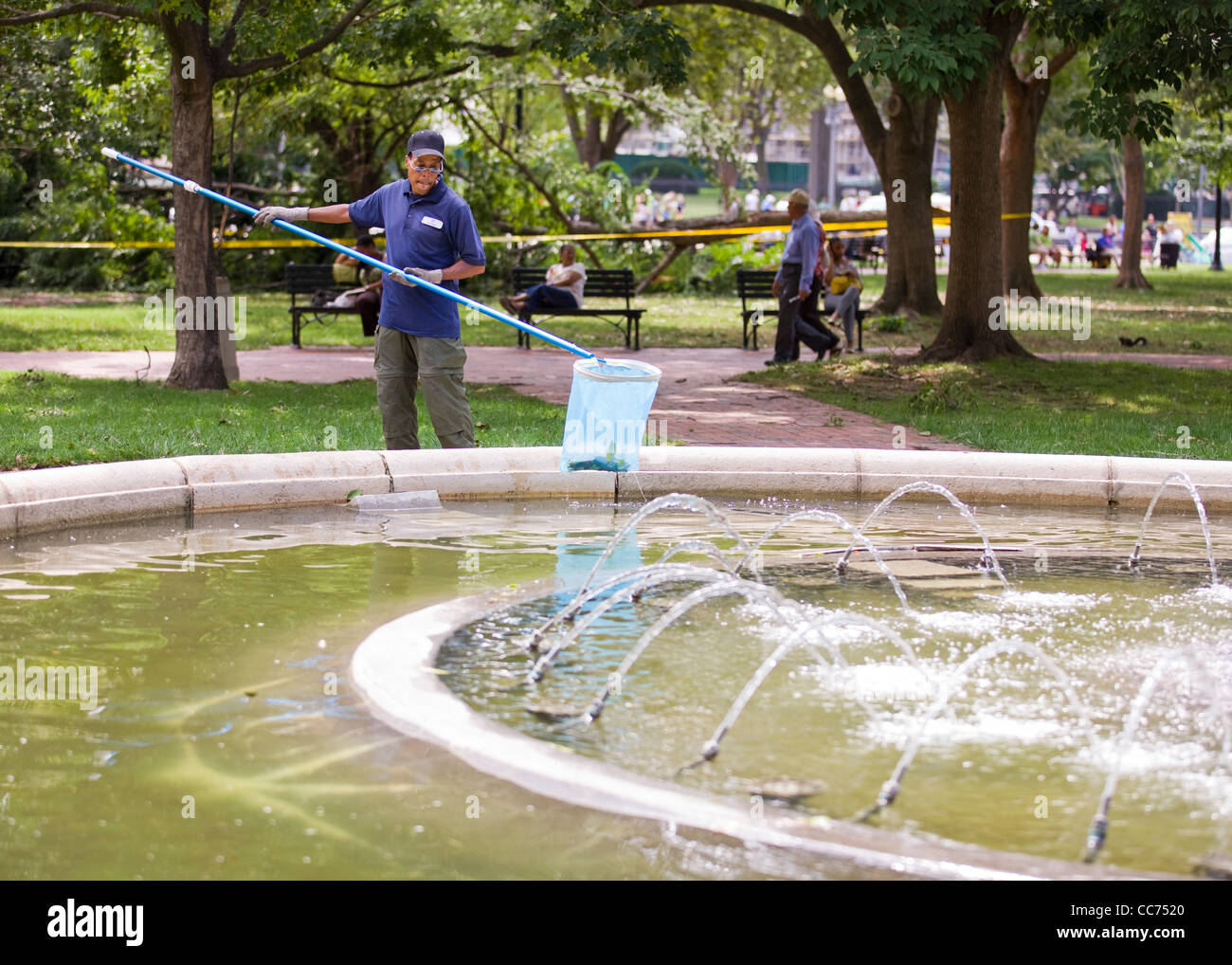 Maintenance man removing debris from park water fountain Stock Photo