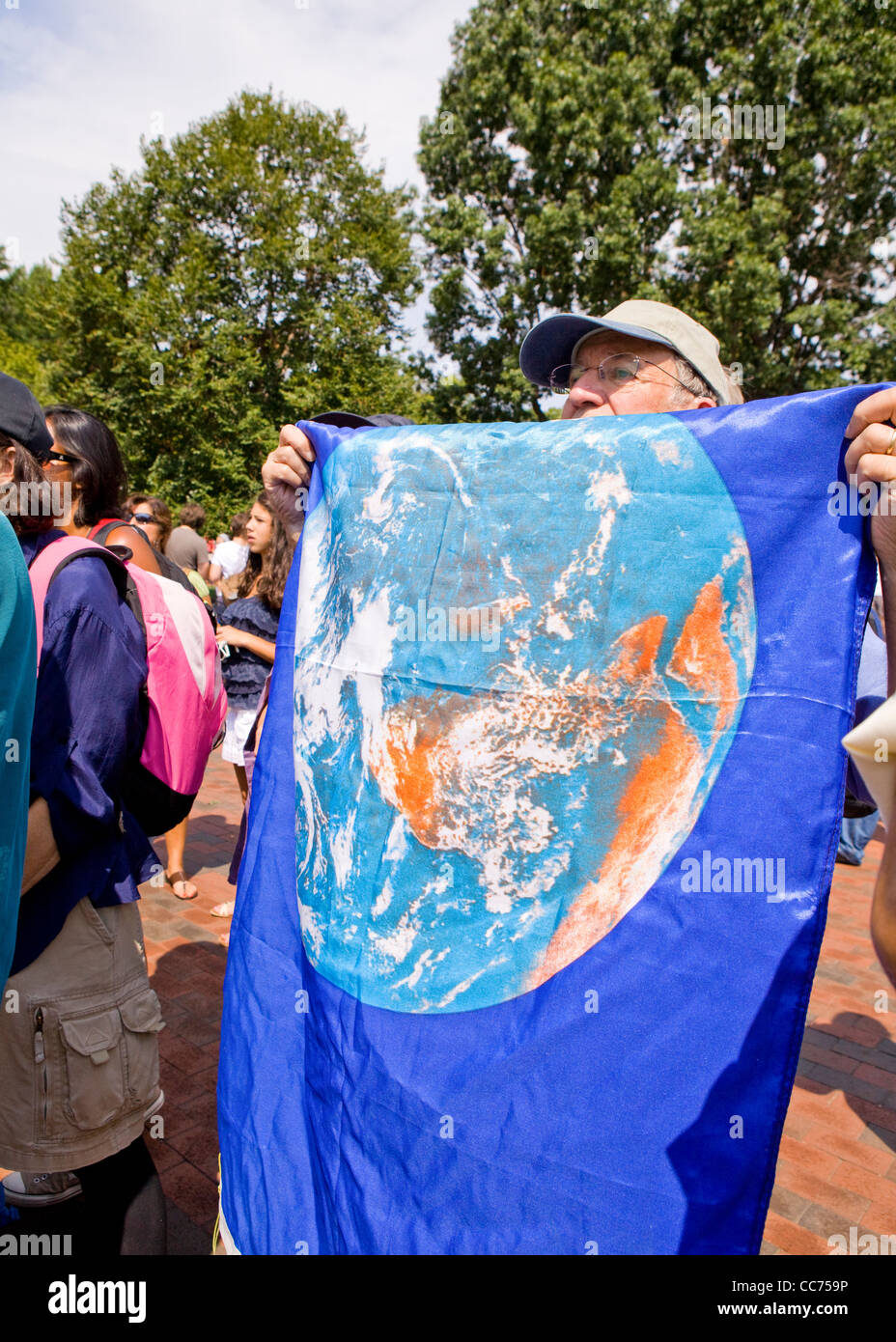 An elderly demonstrator holding up an earth flag Stock Photo