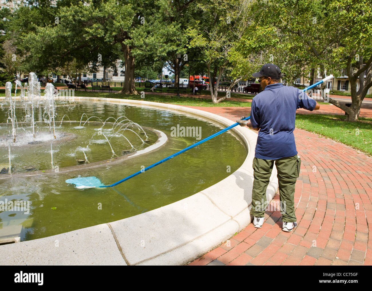 Maintenance man removing debris from park water fountain Stock Photo