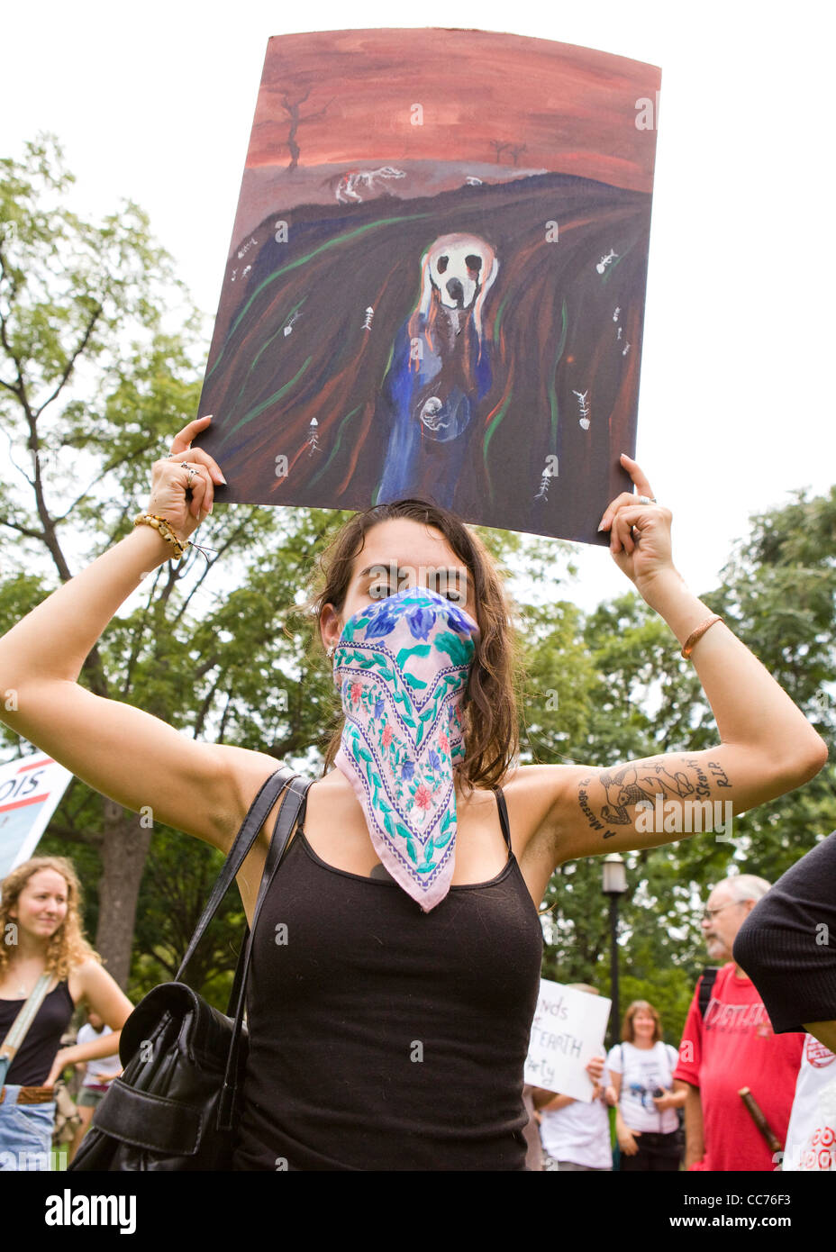 A young woman wearing a bandana mask and holding up The Scream painting during an environmental  protest (environmental activist) - Washington, DC USA Stock Photo