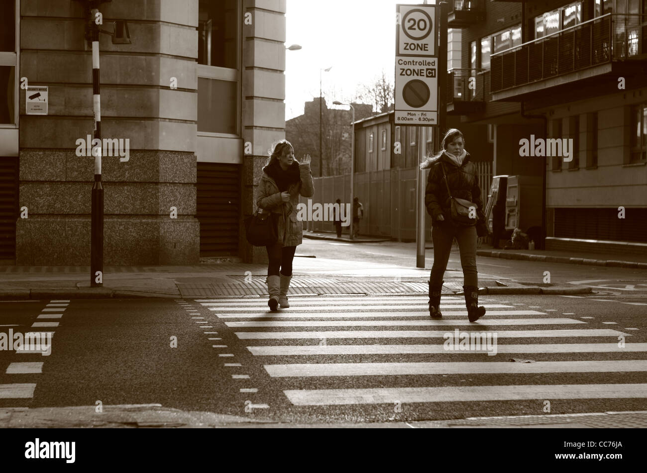 two females walk across a zebra crossing in London, photographed in sepia Stock Photo