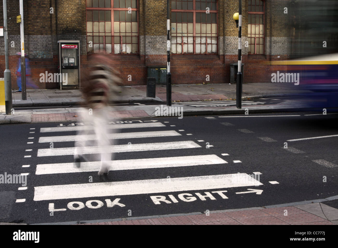 a blurred figure walks across a zebra crossing in London Stock Photo
