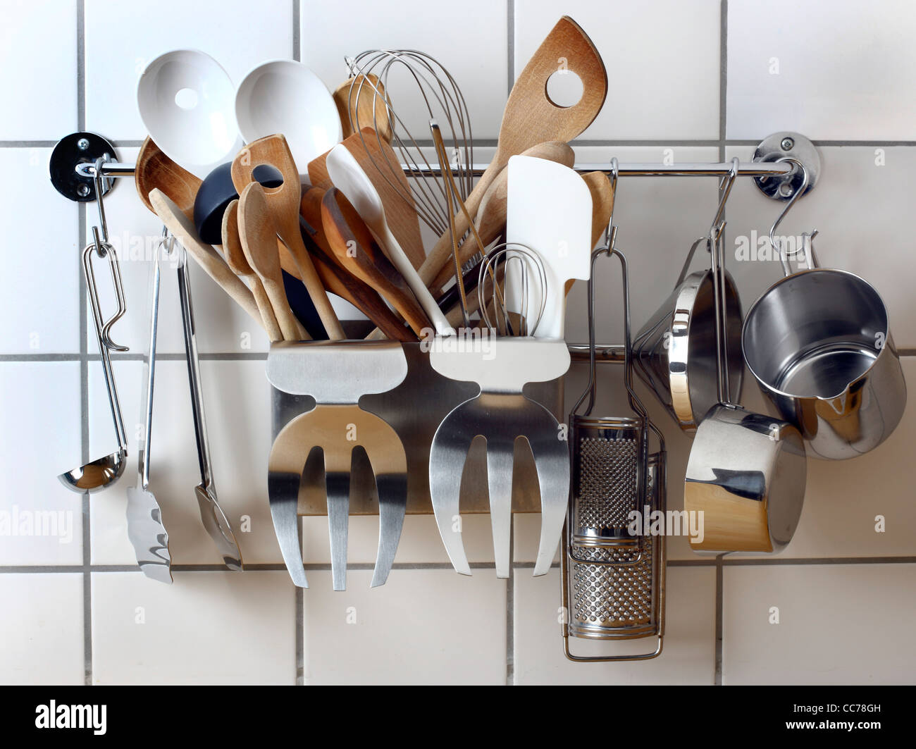 Various kitchen utensils, kitchen tools, hanging at a kitchen wall rack. Stock Photo
