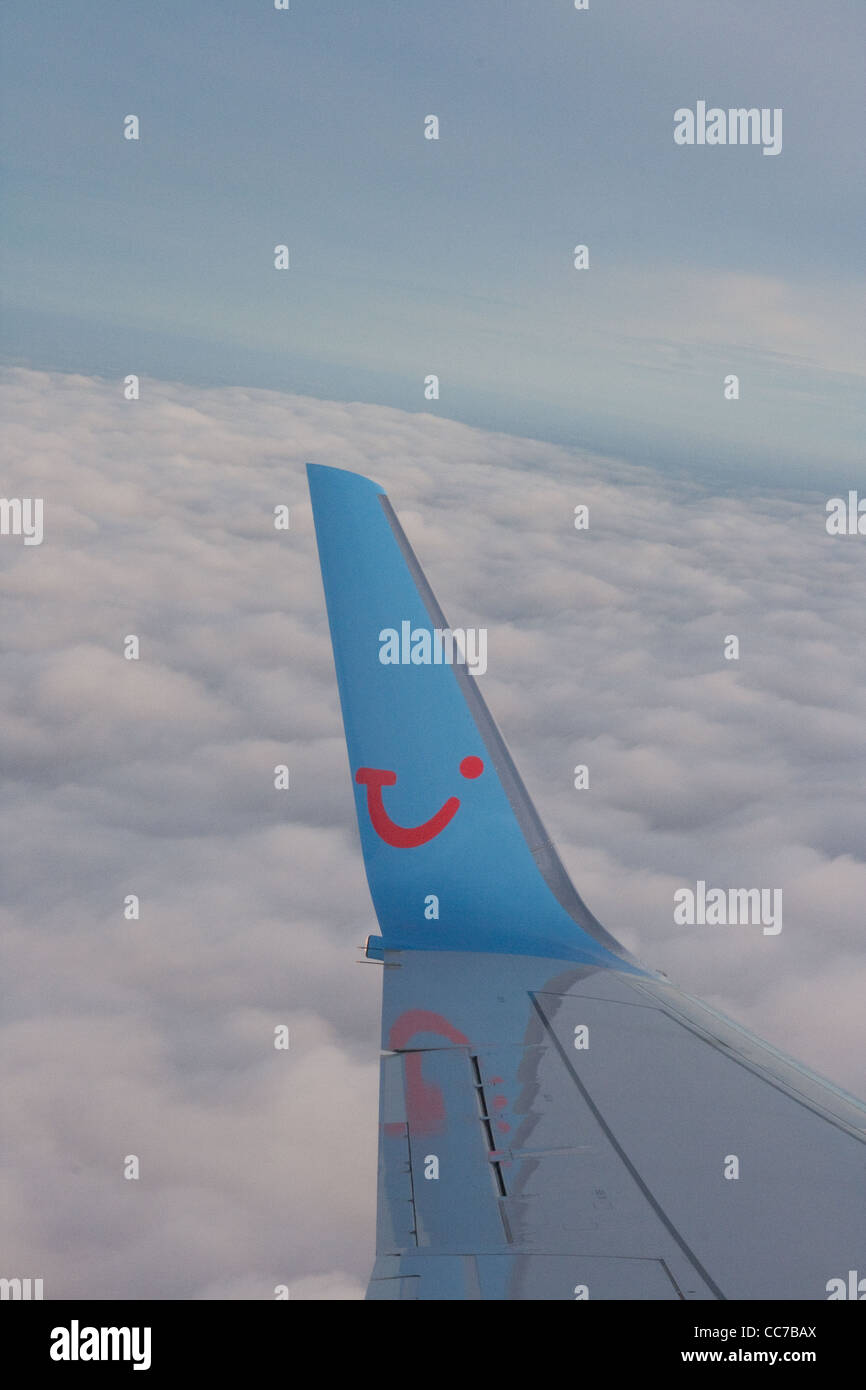 Wingtip of Thomson Airways Airbus flying above cloudbase Stock Photo