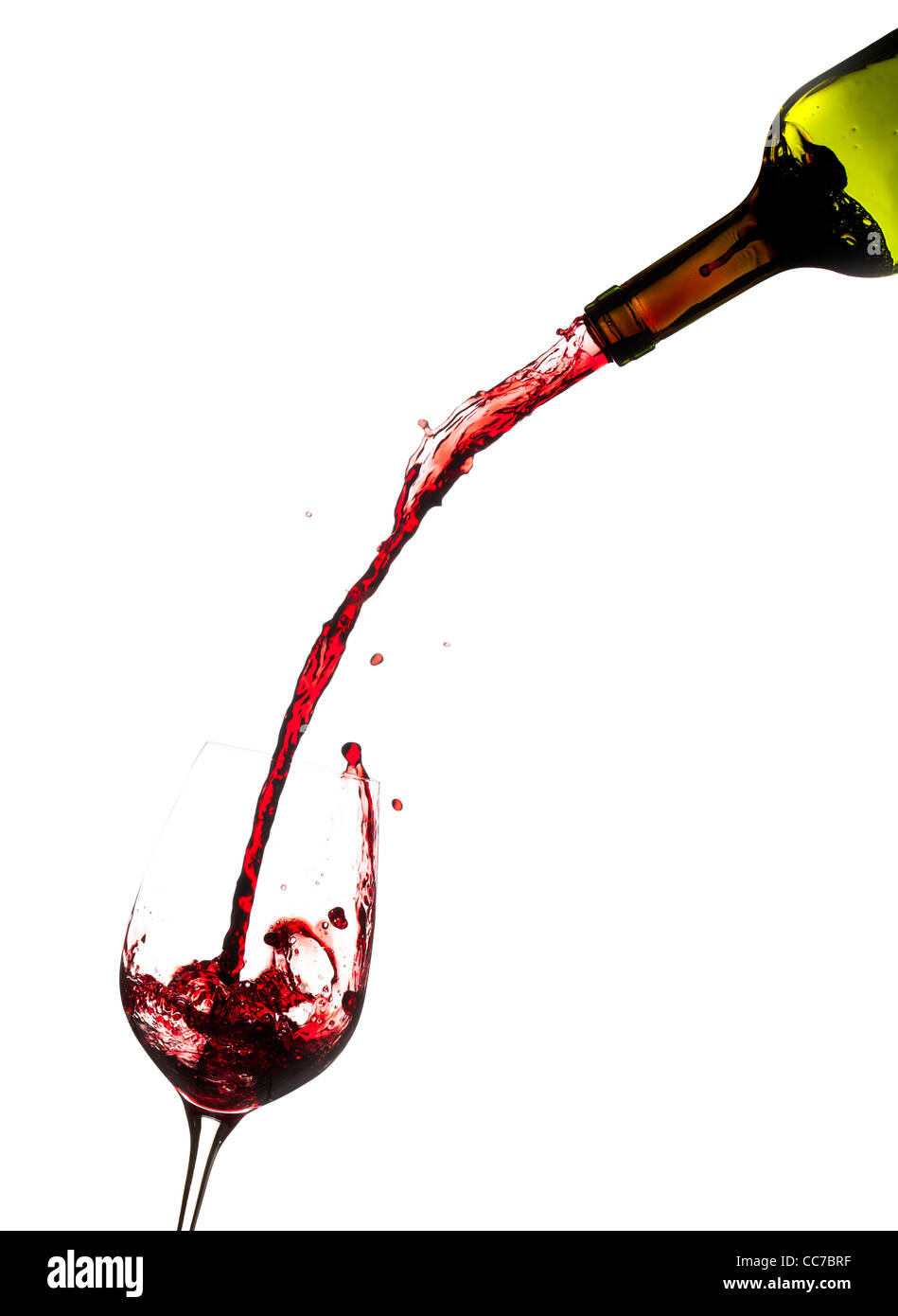 Red wine being poured rapidly directly from the bottle into a large wine glass Stock Photo