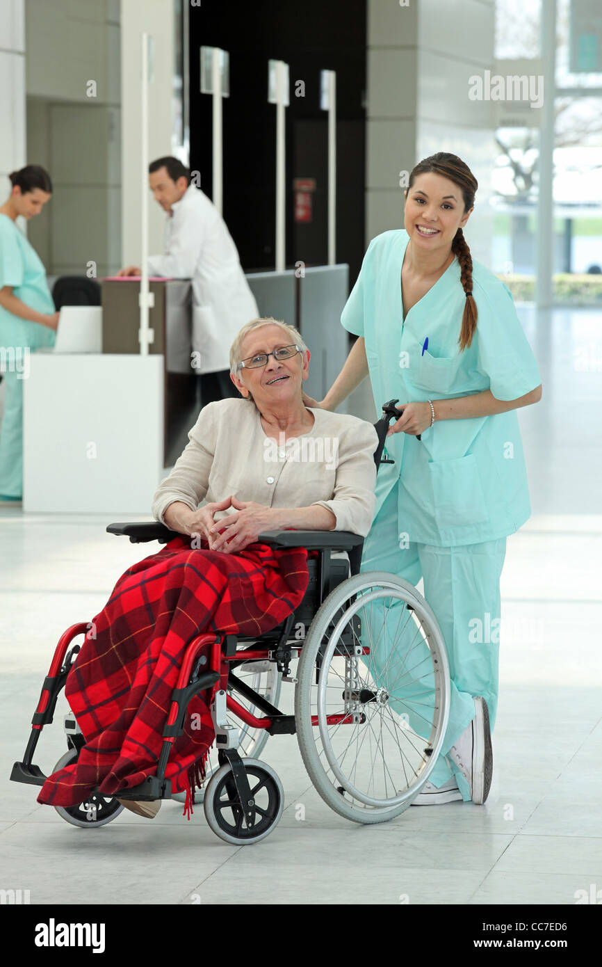 Nurse pushing an older woman in a wheelchair Stock Photo - Alamy