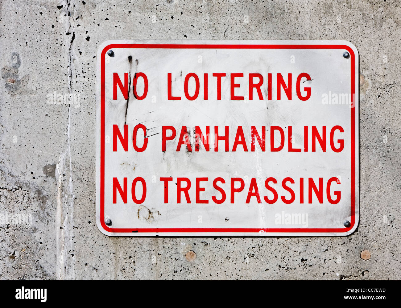 no loitering, panhandling, trespassing sign on concrete wall Stock Photo