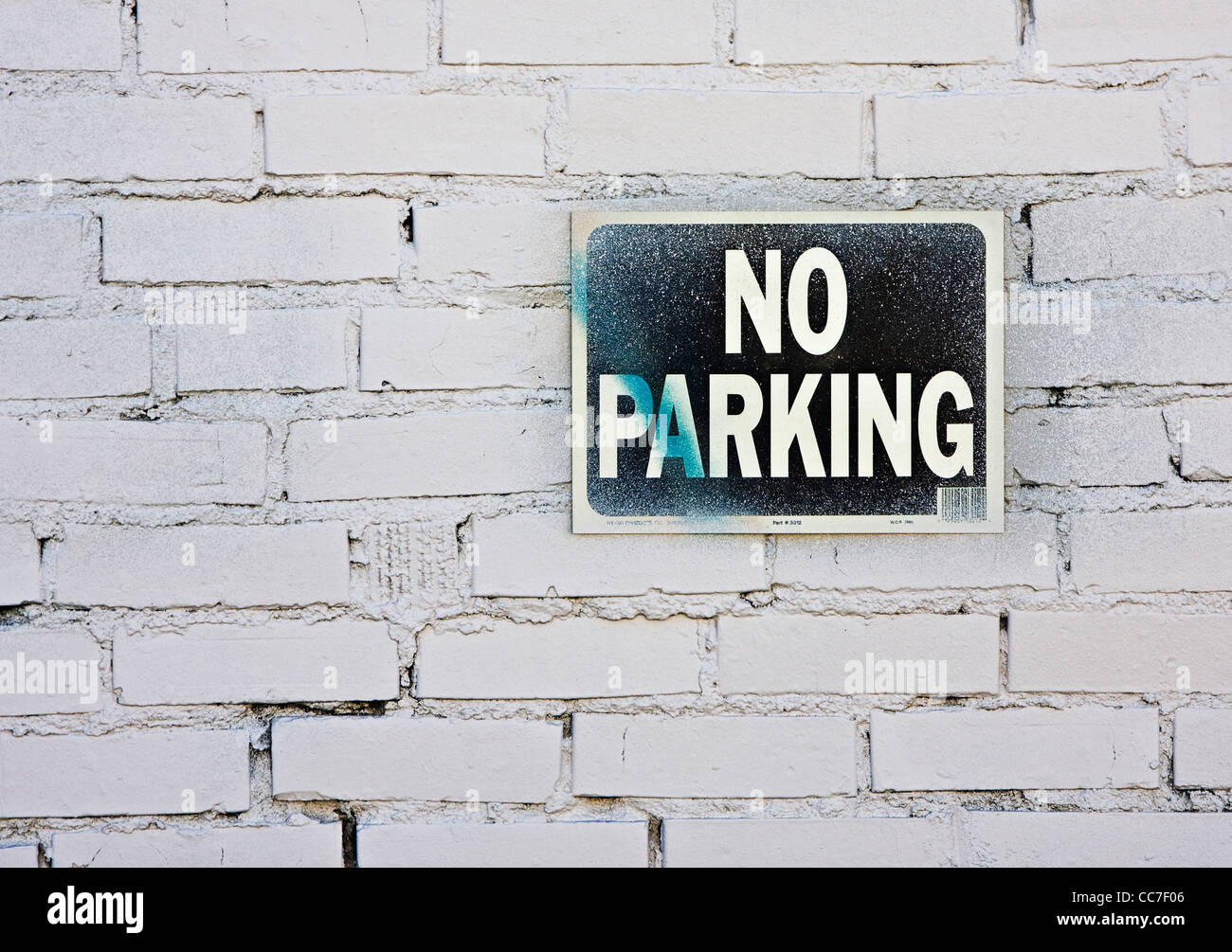 old no parking sign mounted on white painted brick wall Stock Photo