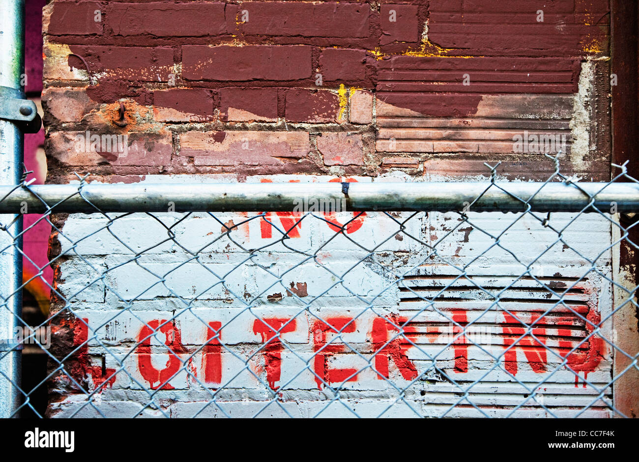 no loitering sign painted in wall behind chain link fence Stock Photo