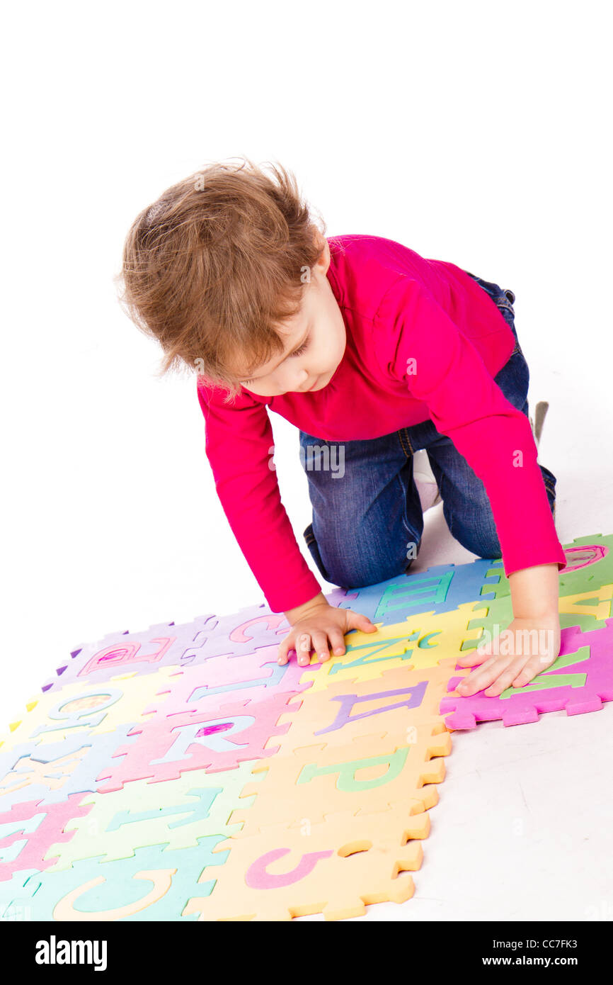 Little cute girl solving alphabet puzzle over white background Stock Photo