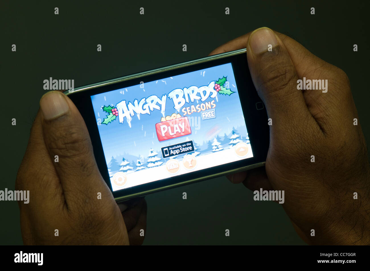 Man Playing Angry birds seasons game in iphone Stock Photo
