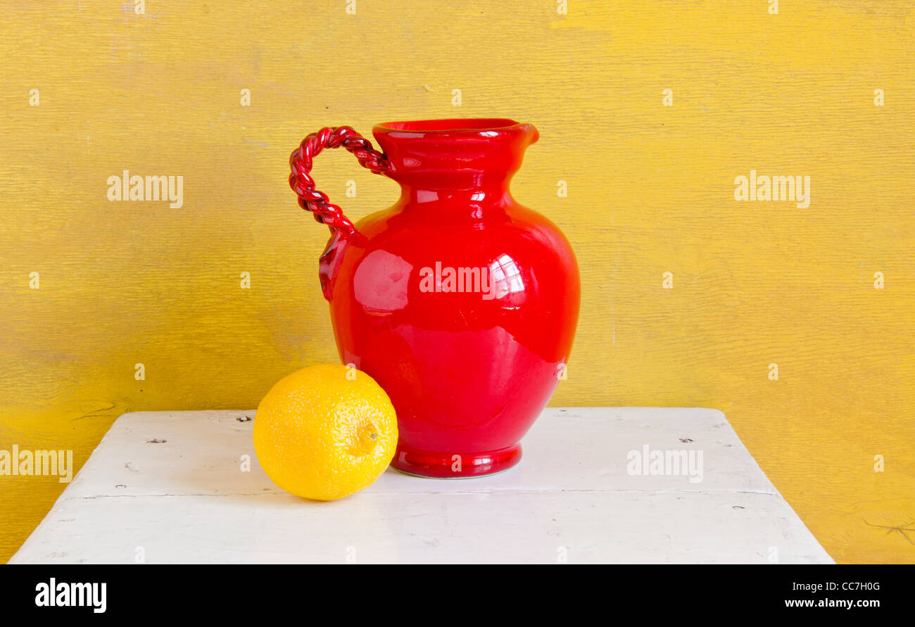 Still life. Red vase and yellow lemon on a shelf. Stock Photo