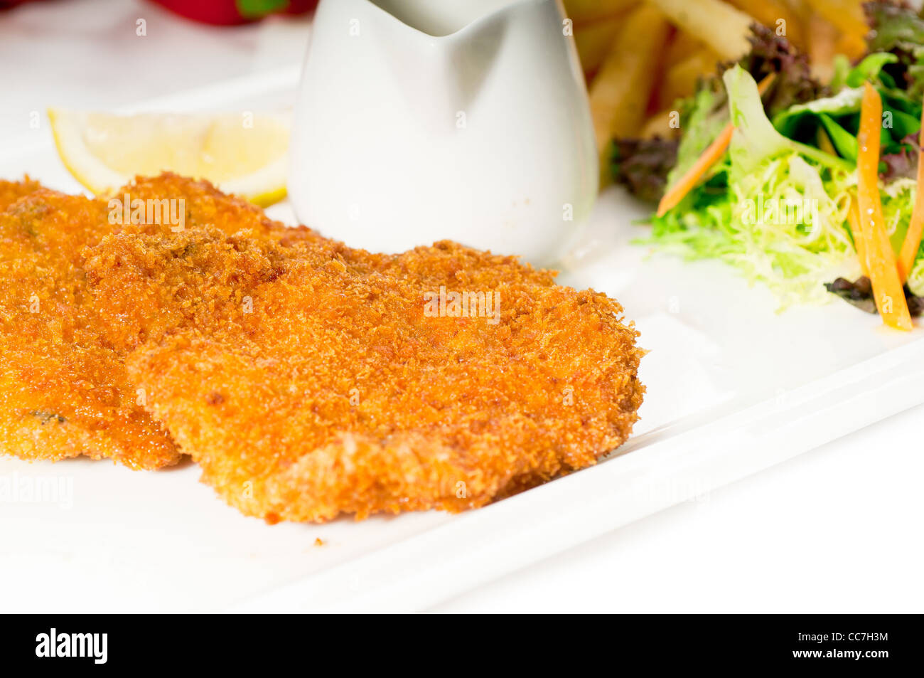 classic breaded Milanese veal cutlets with french fries and vegetables on background ,MORE
