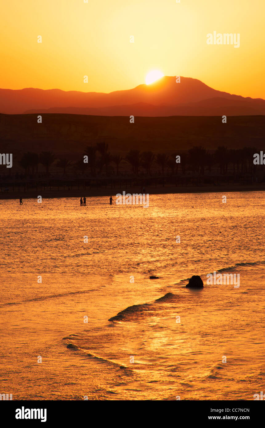 Sunset over Marsa Alam in Egypt with lapping waves over the reef in the foreground Stock Photo