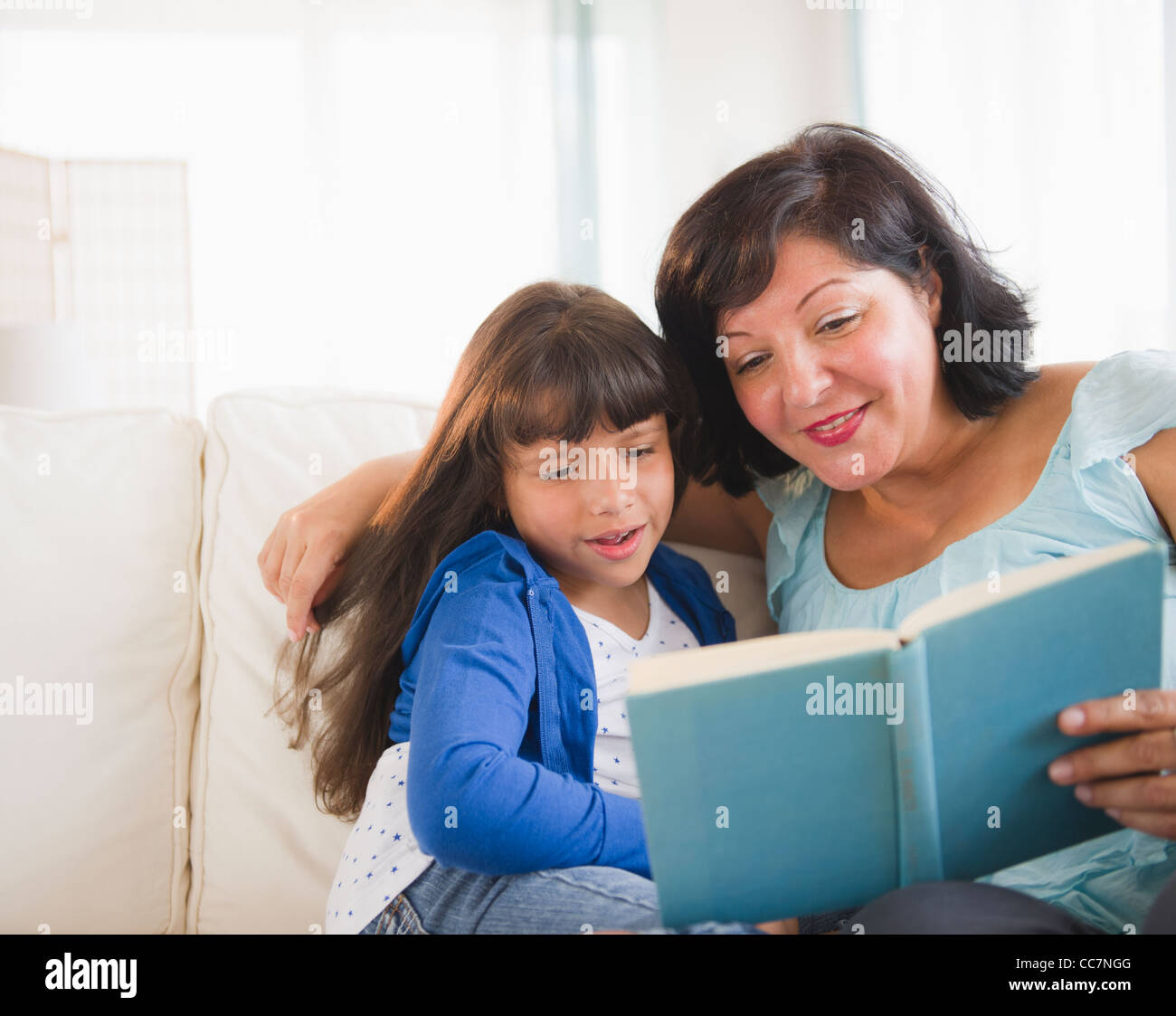 Hispanic mother and daughter reading a book Stock Photo