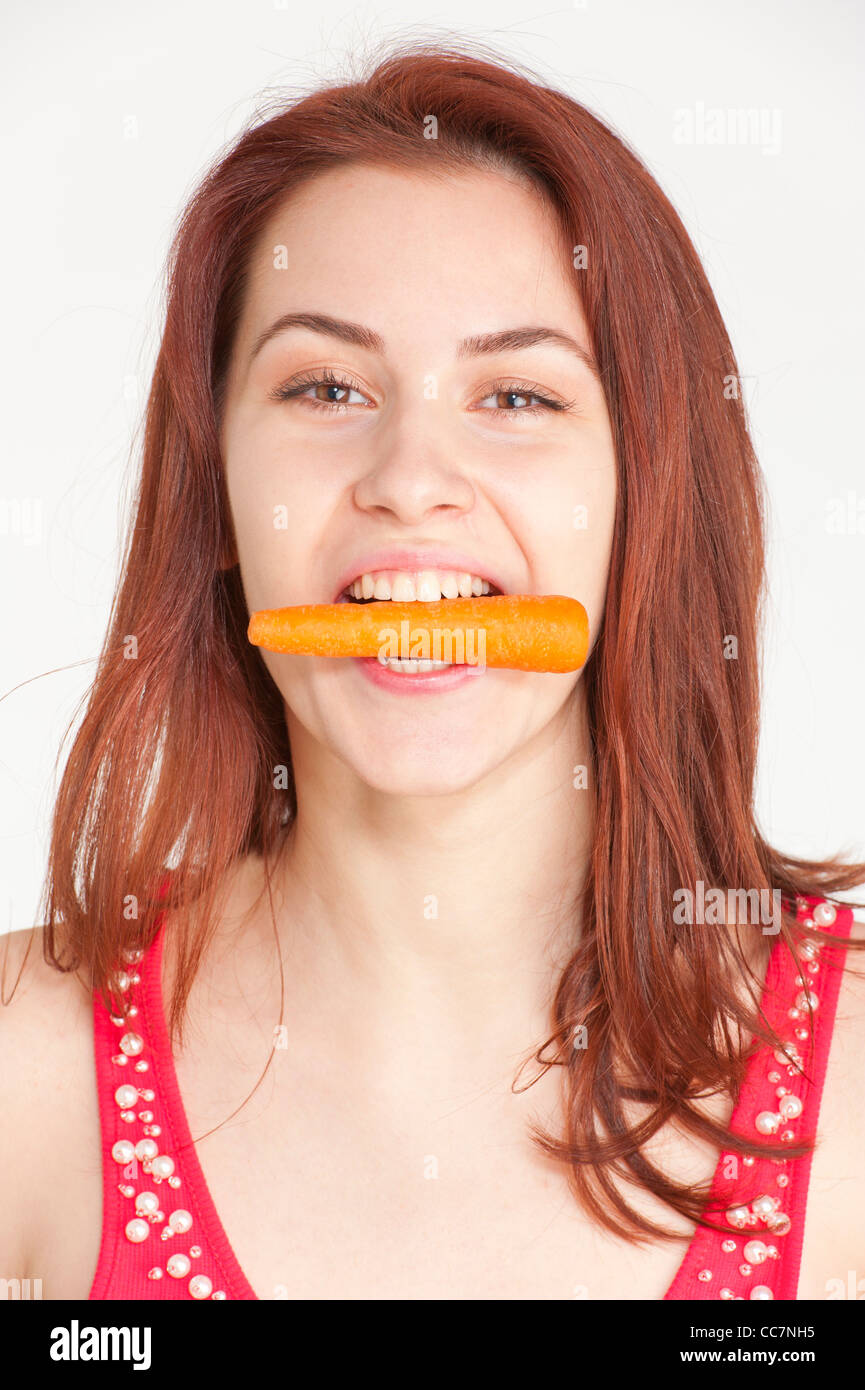 Young woman biting on an organic carrot Stock Photo