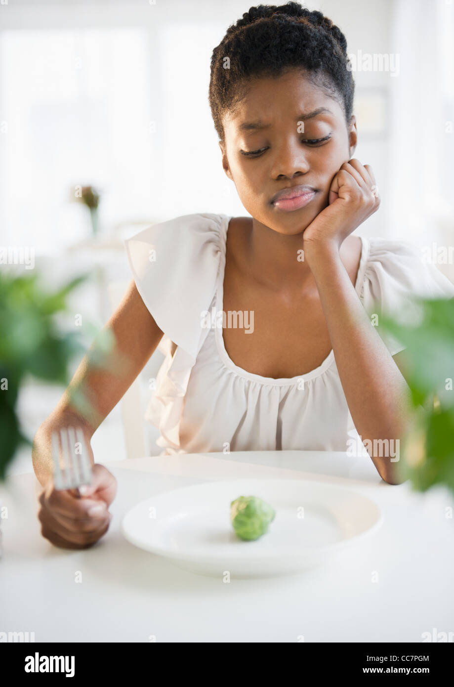 Frustrated Black woman looking at brussels sprout Stock Photo