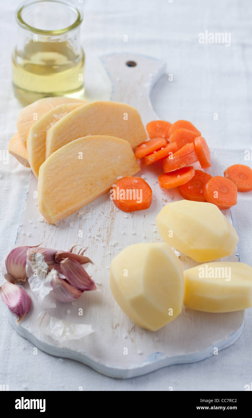 Ingredients on a chopping board to make roast potatoes Stock Photo