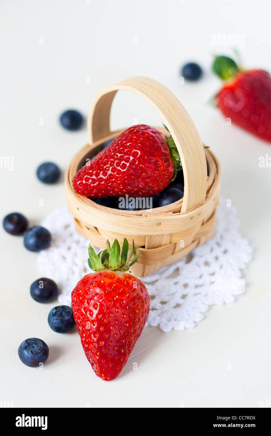 Strawberries and blueberries in a basket on a crochet doily Stock Photo
