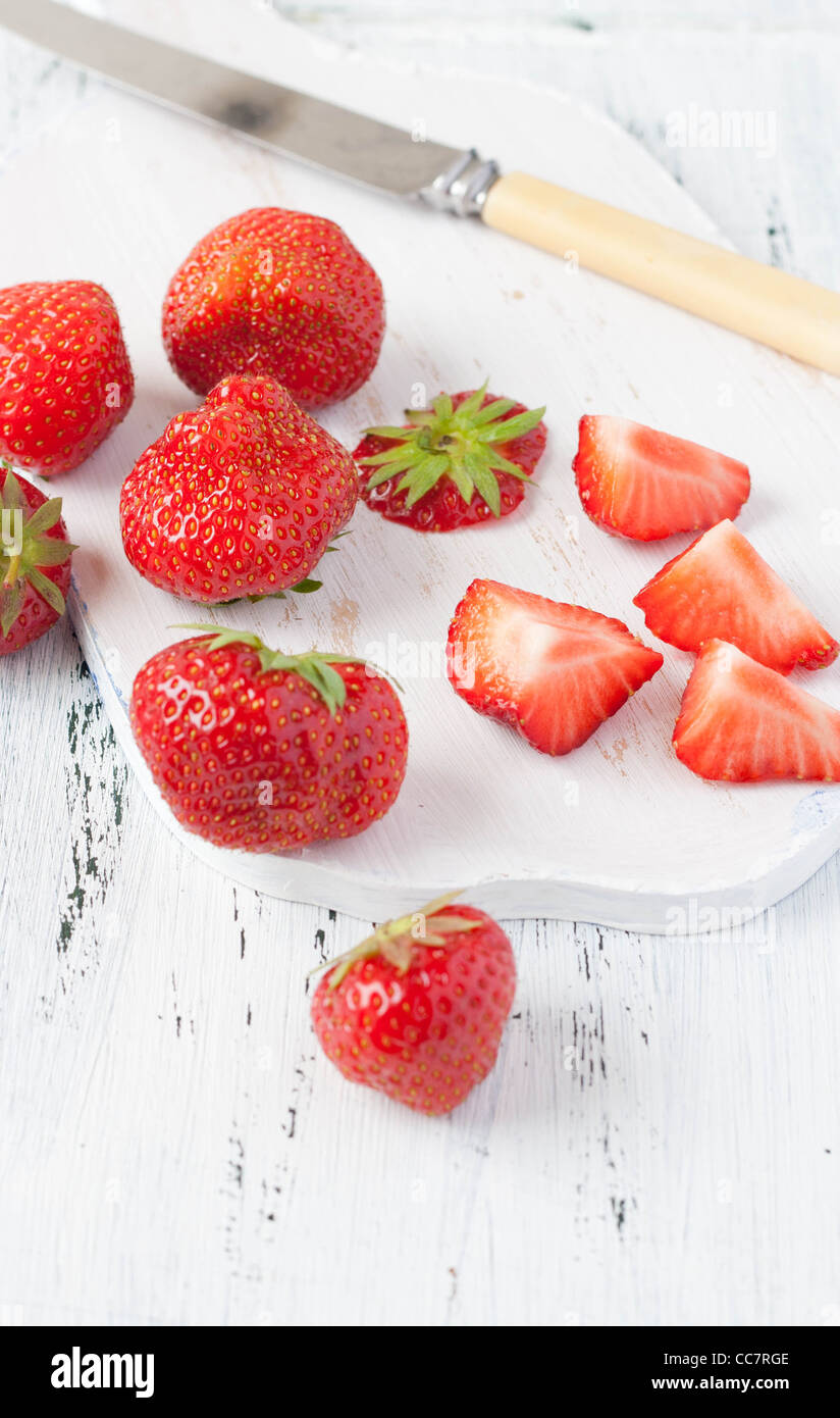 Strawberries on a white chopping board with a white knife Stock Photo