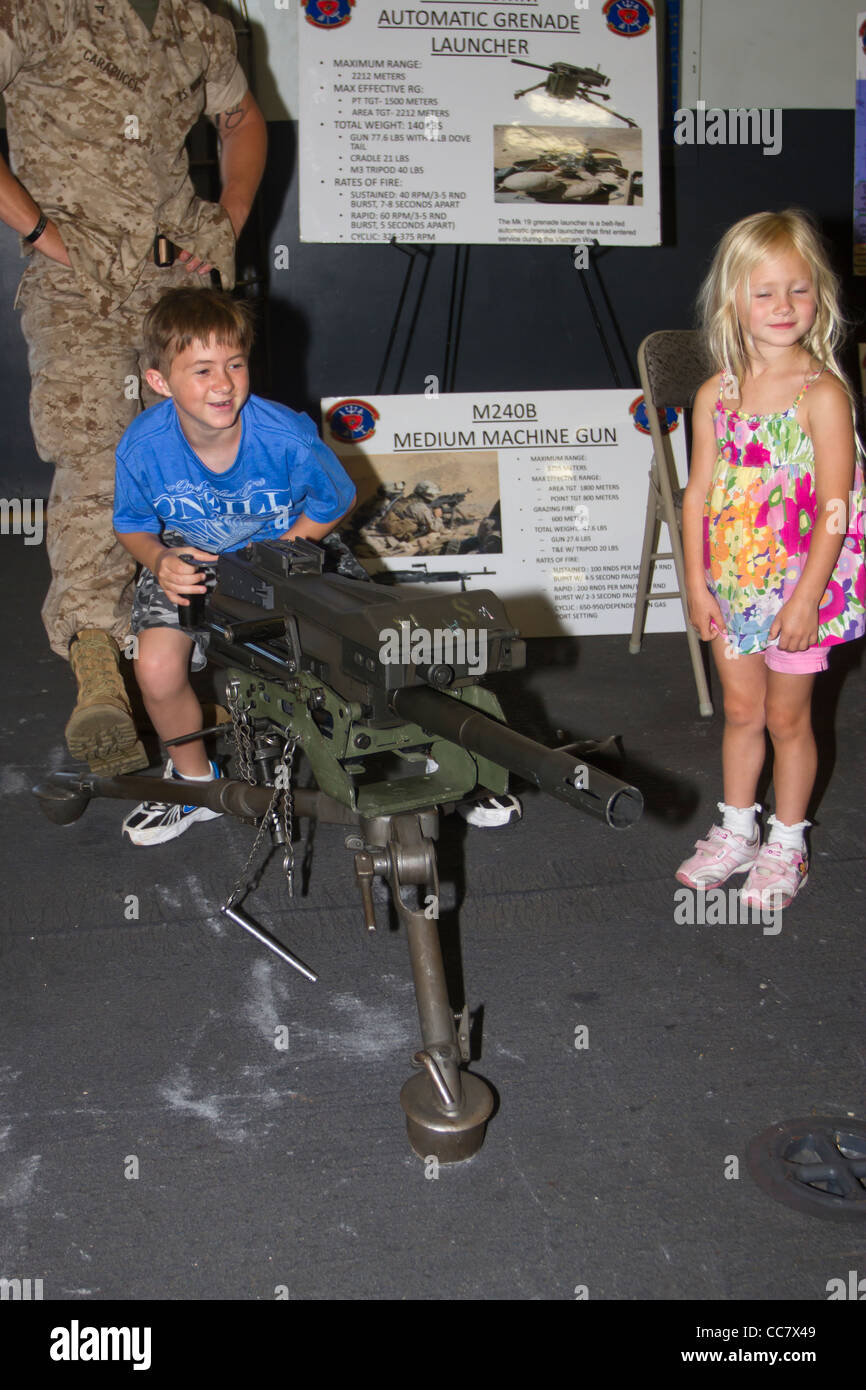 A young boy plays with a machine gun on the USS Iwo Jima while his sister looks on during Fleet Week 2011 in New York City Stock Photo