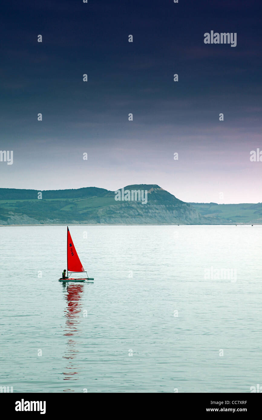 A lone 'Topper' sailing dinghy in the English Channel off Lyme Regis