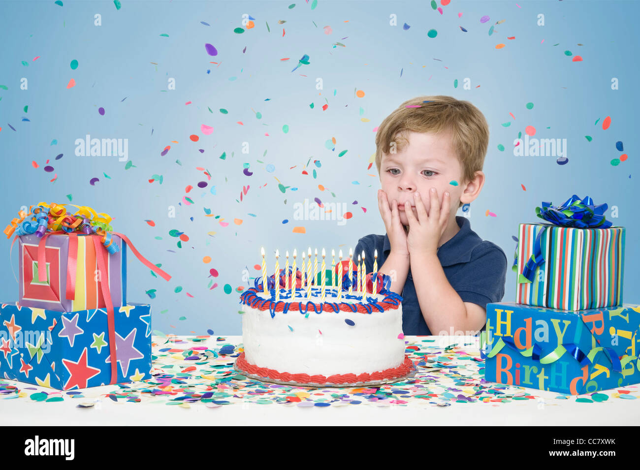 Young Boy with Birthday Presents and Making a Wish before Blowing Out