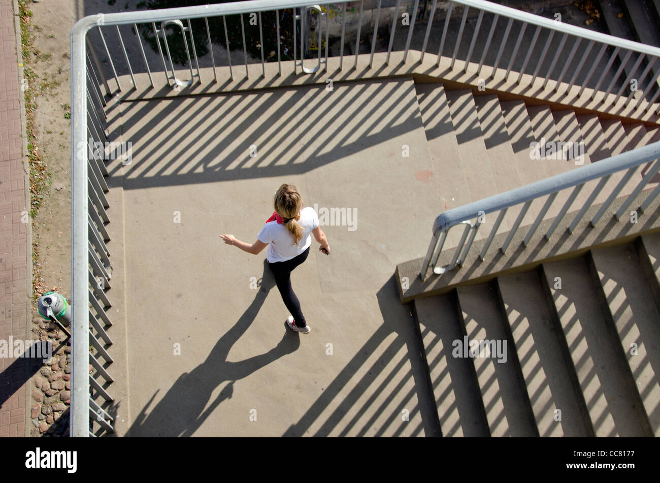 Girl Setting of downstairs. Stairs, railings sunlight and shadows. Stock Photo