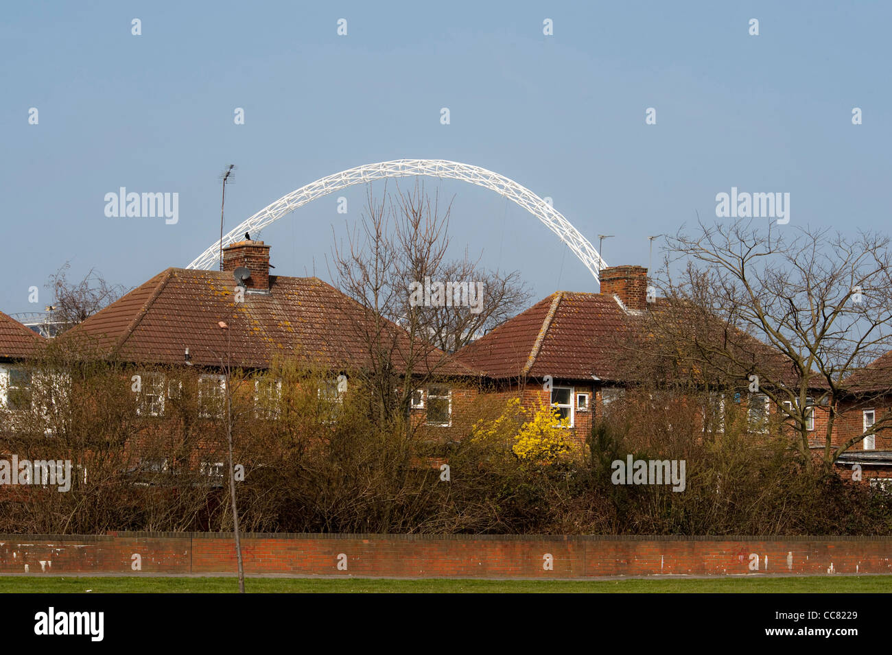 The arch of Wembley stadium in the London borough of Brent with houses and trees in front Stock