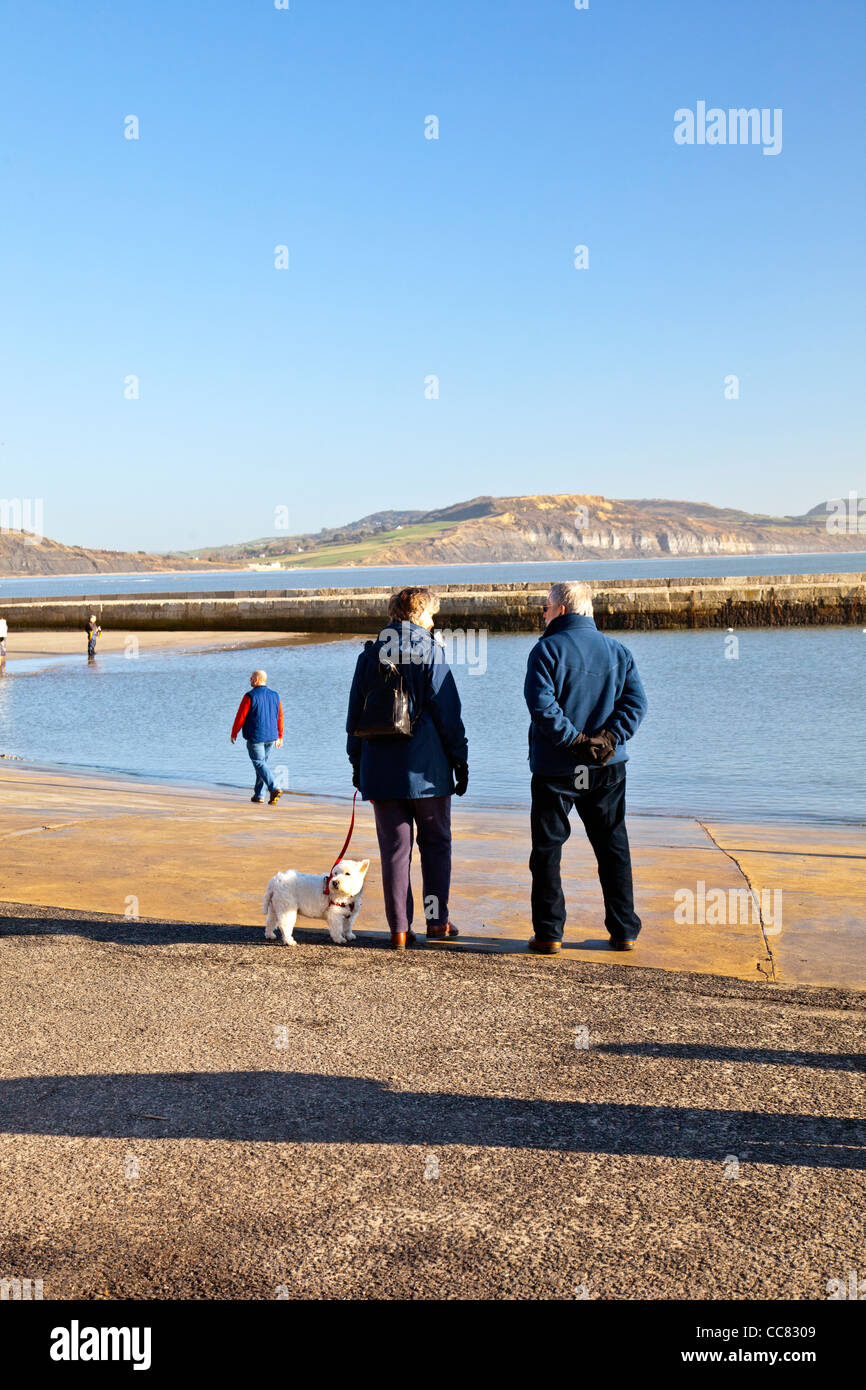 Two pet owners and their dog at the harbour in Lyme Regis on a winter