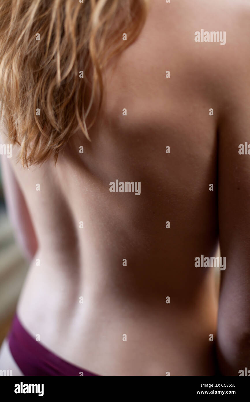 Young woman standing with nude back towards camera. Stock Photo